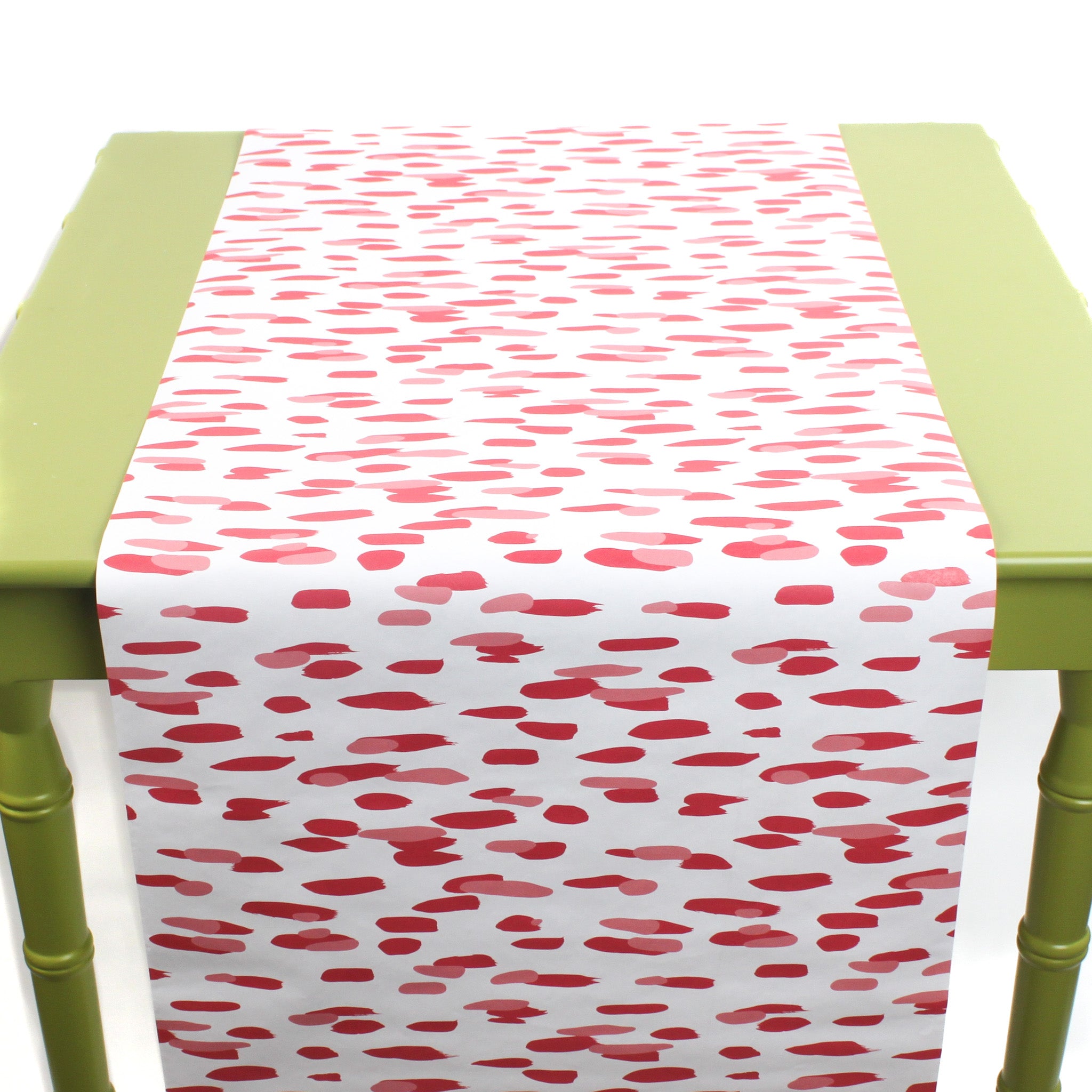a green table covered with A pink and white paper table runner with a brushtroke pattern on a white background
