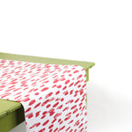 a green table covered with A pink and white paper table runner with a brushtroke pattern on a white background