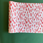A white and red paper table runner featuring a brushtroke pattern called Club House by Madcap Cottage