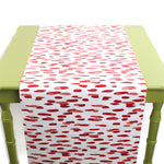 a green table covered by a white and red paper table runner featuring a brushtroke pattern called Club House by Madcap Cottage
