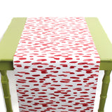 a green table covered by a white and red paper table runner featuring a brushtroke pattern called Club House by Madcap Cottage