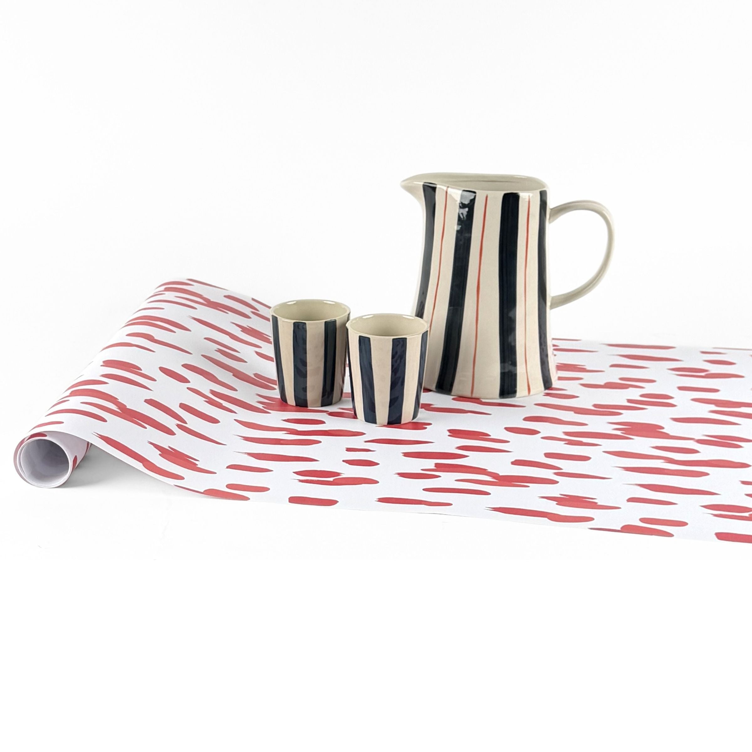 Clubhouse red paper table runner styled with striped pitcher and matching cups.