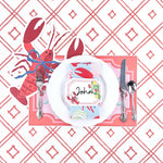 Coastal themed table setting featuring a lobster place card, lobster shaped placemat, white dinner plate, and coral trellis patterned background.