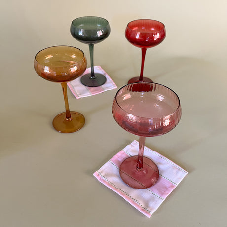 colored coupe glasses with cocktail napkins