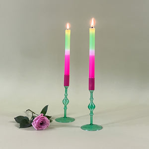 two green colored glass candle holders with pink tops and pastel taper candles