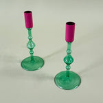 two green colored glass candle holders with pink tops