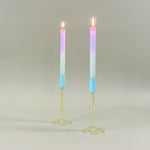 two yellow colored glass candle holders with blue tops holding pastel taper candles
