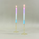 two yellow colored glass candle holders with blue tops holding pastel taper candles