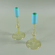 two yellow colored glass candle holders with blue tops