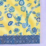 corner of a yellow chinoiserie tea towel with blue cherry blossom motifs.