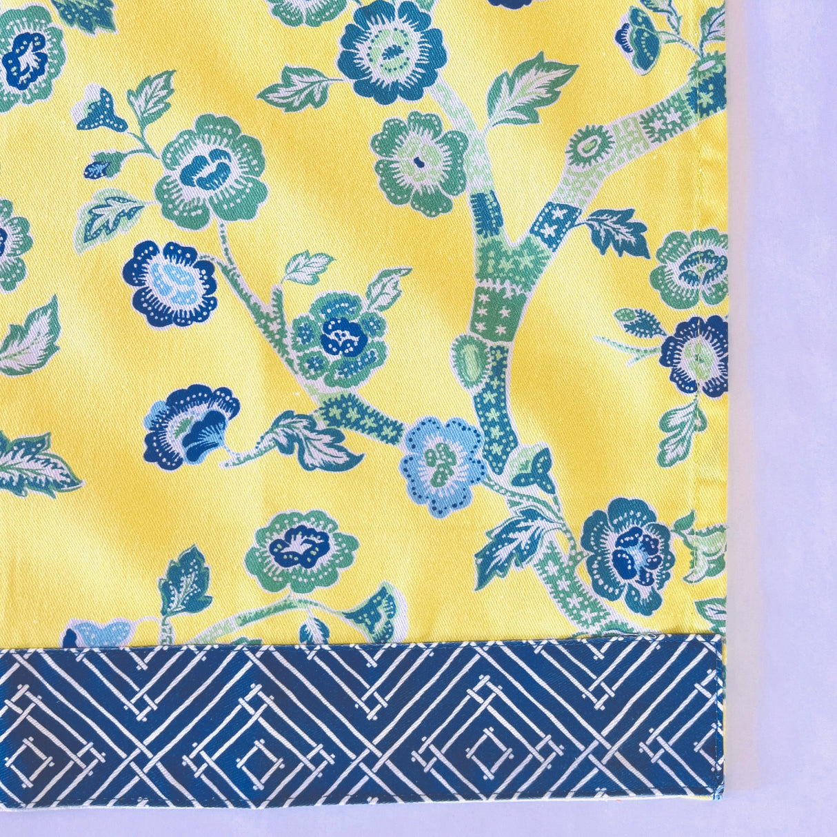 corner of a yellow chinoiserie tea towel with blue cherry blossom motifs. 