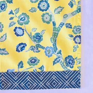 corner of a yellow chinoiserie tea towel with blue cherry blossom motifs. 