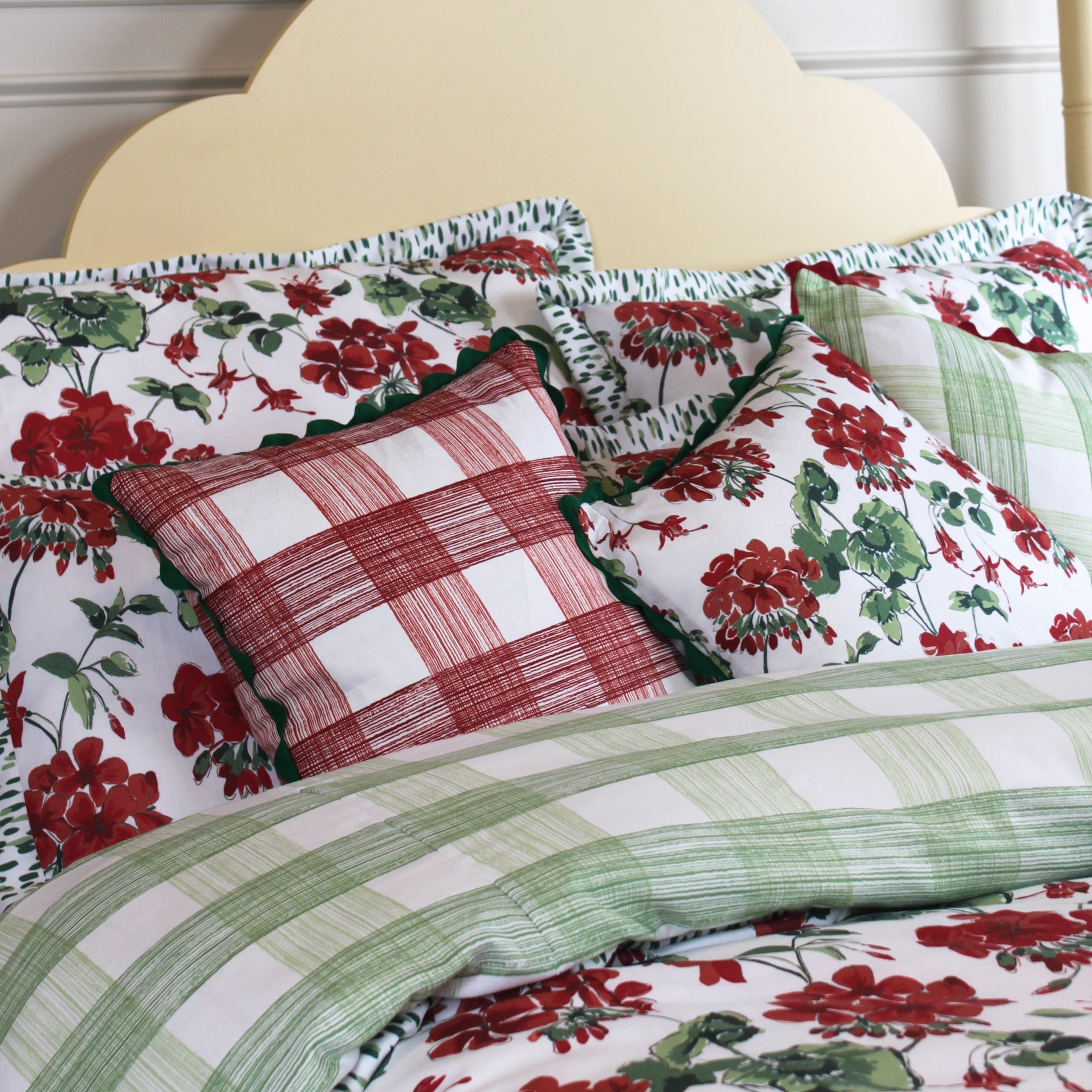red geranium and plaid patterned pillows on a bed with green and red colors.