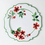 A white tole metal floral charger plate decorated with red geraniums with a green border against a white background. 