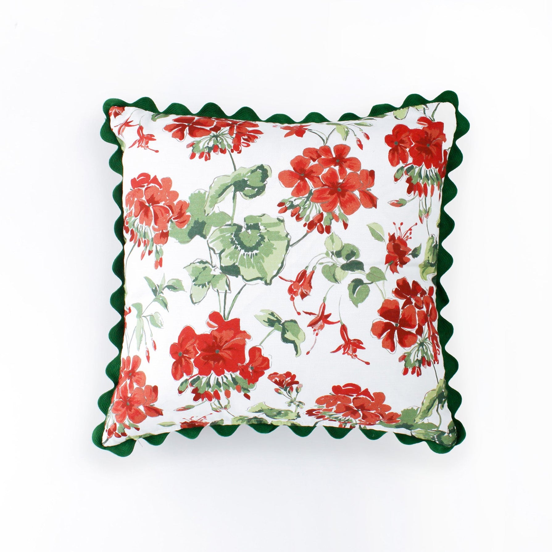 Square decorative pillow featuring a red and green floral geranium pattern on a white background, finished with a dark green scalloped trim around the edges.