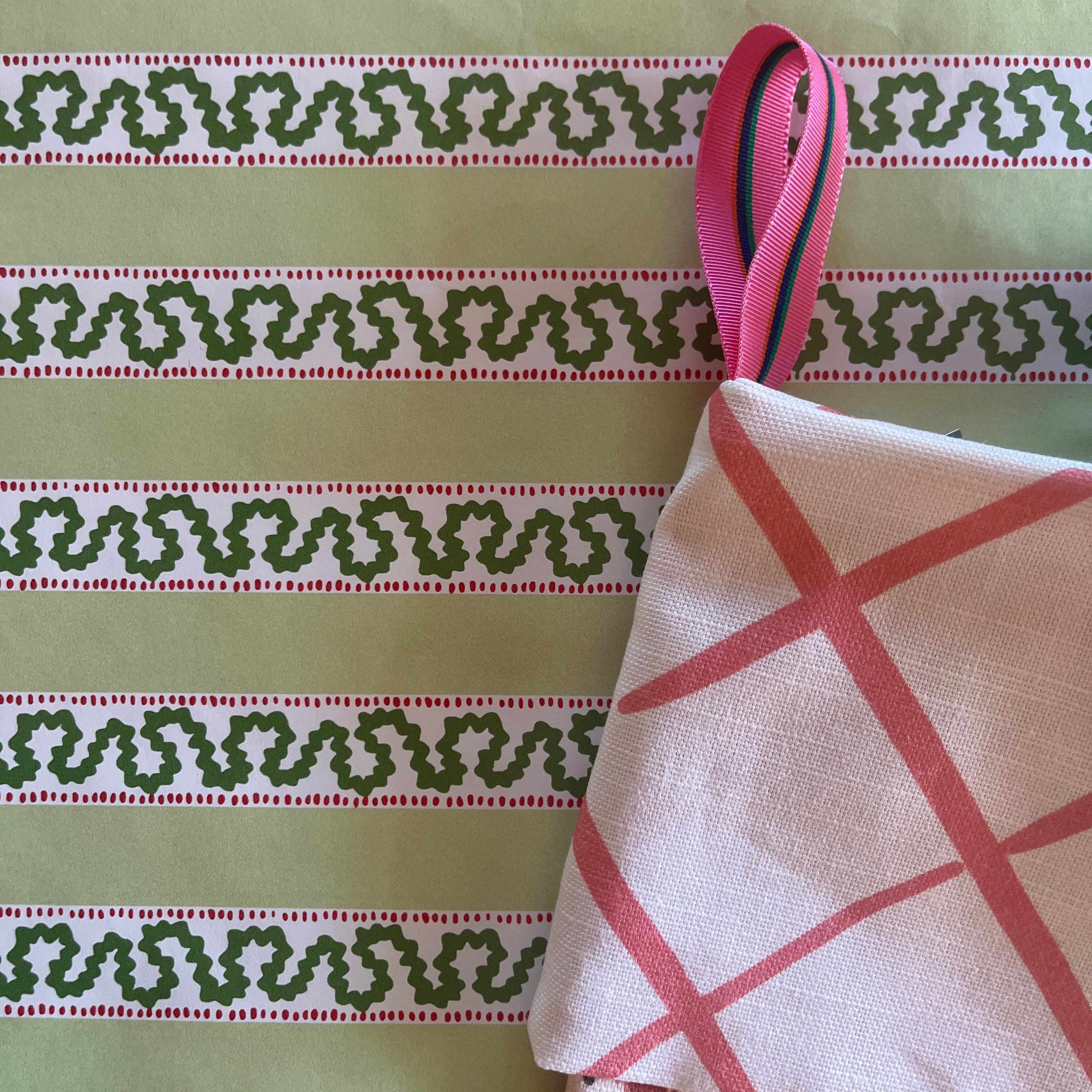 a pink christmas stocking with a pink and white lattice design cuff and a pink and yellow chinoiserie pattern stocking. 