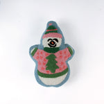 Snowman-shaped decorative pillow with a hooked texture, featuring a smiling snowman wearing a pink sweater with a green Christmas tree design and a matching blue and pink hat.