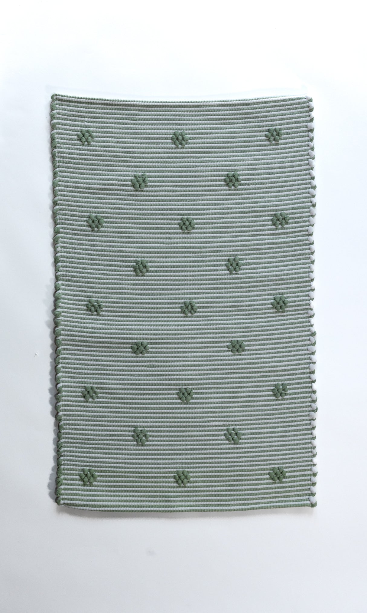 A rectangular green accent rug with small daisy shaped accents scattered across it. 