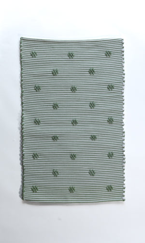A rectangular green accent rug with small daisy shaped accents scattered across it. 
