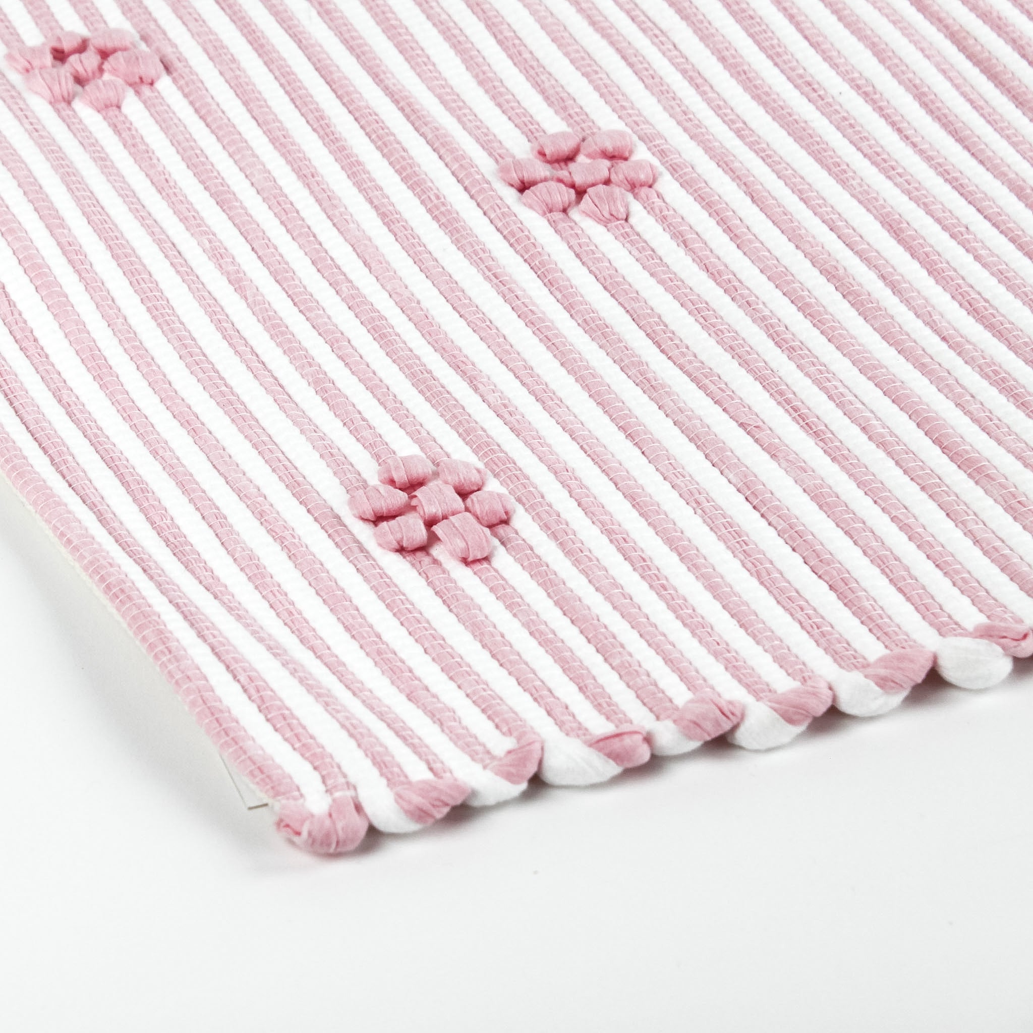 close up of A pink accent rug with a daisies pattern on it