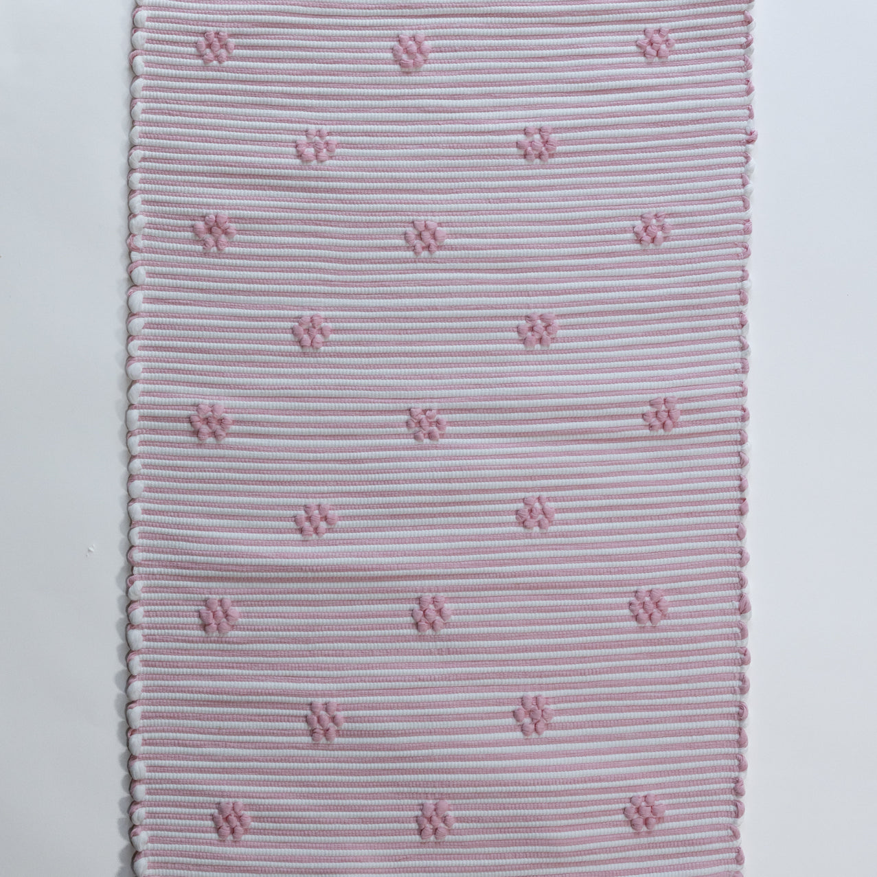 A madcap cottage pink accent rug with small daisy motifs across the front. 