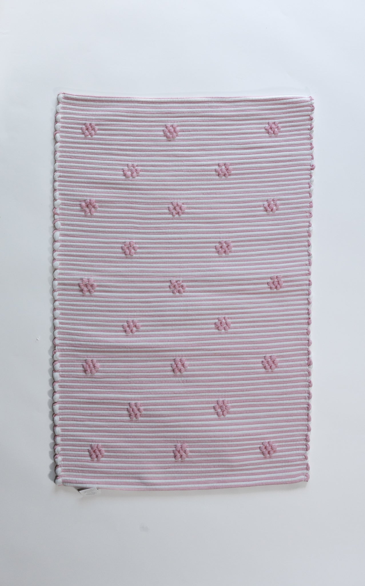 A madcap cottage pink accent rug with small daisy motifs across the front. 