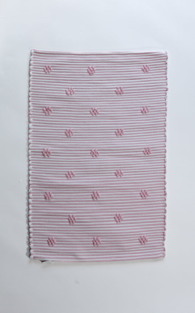 A madcap cottage pink accent rug with small daisy motifs across the front. 
