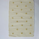 A rectangular yellow accent rug with small daisy shaped accents scattered across it. 
