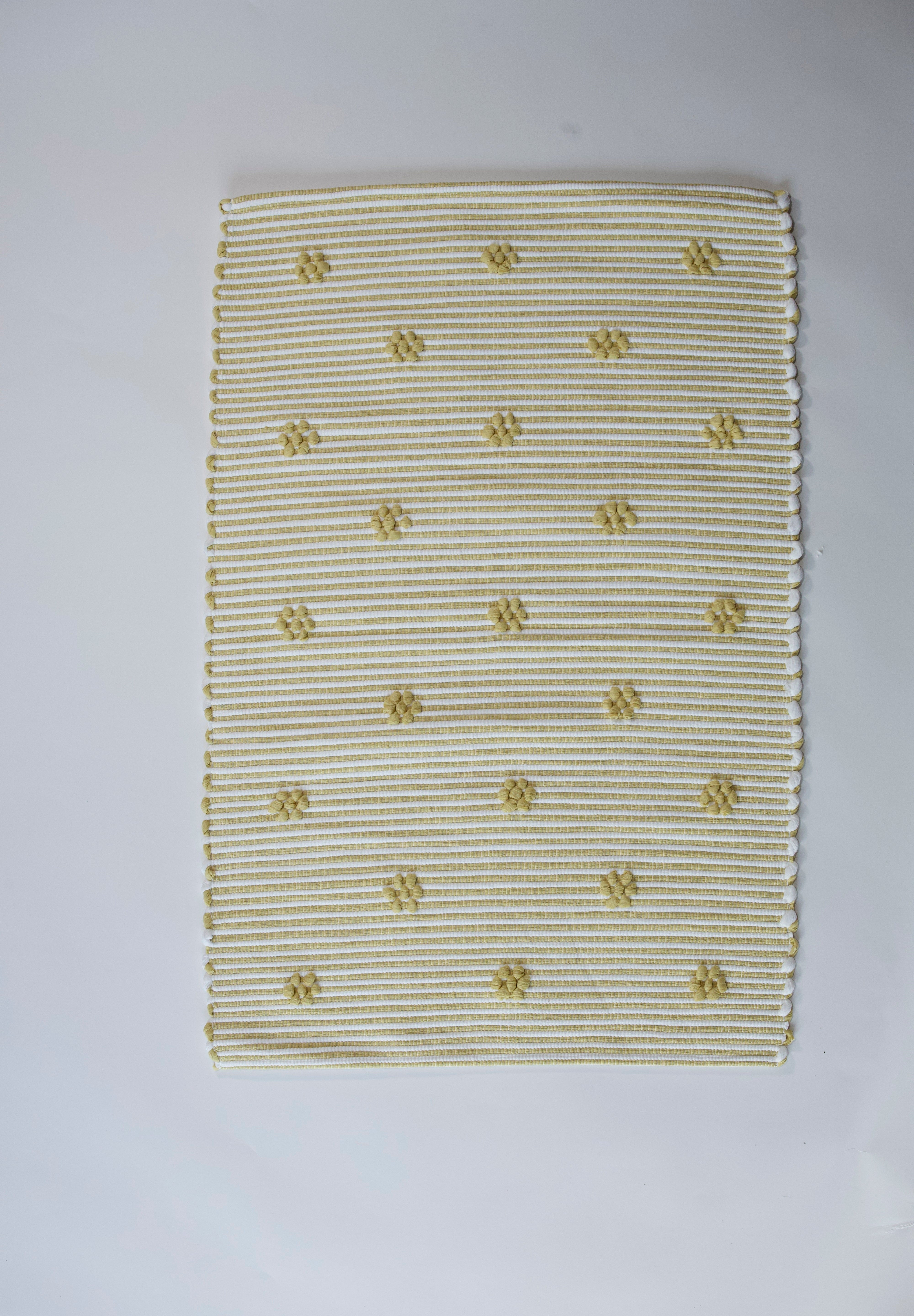 A rectangular yellow accent rug with small daisy shaped accents scattered across it. 