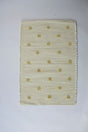 A rectangular yellow accent rug with small daisy shaped accents scattered across it. 