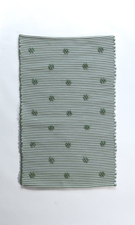 A rectangular green accent rug with small daisy shaped accents scattered across it. 