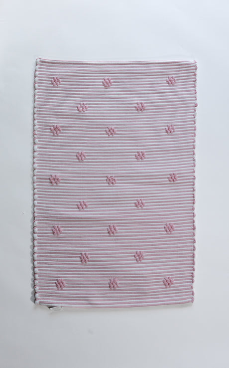 A madcap cottage pink accent rug with small daisy motifs across the front. 