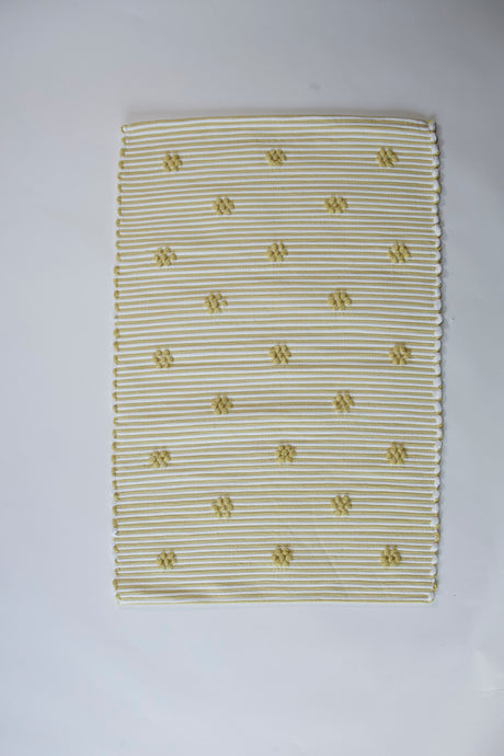 A rectangular yellow accent rug with small daisy shaped accents scattered across it. 
