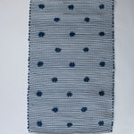 A rectangular navy blue accent rug with small daisy shaped accents scattered across it. 