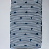 A rectangular navy blue accent rug with small daisy shaped accents scattered across it. 