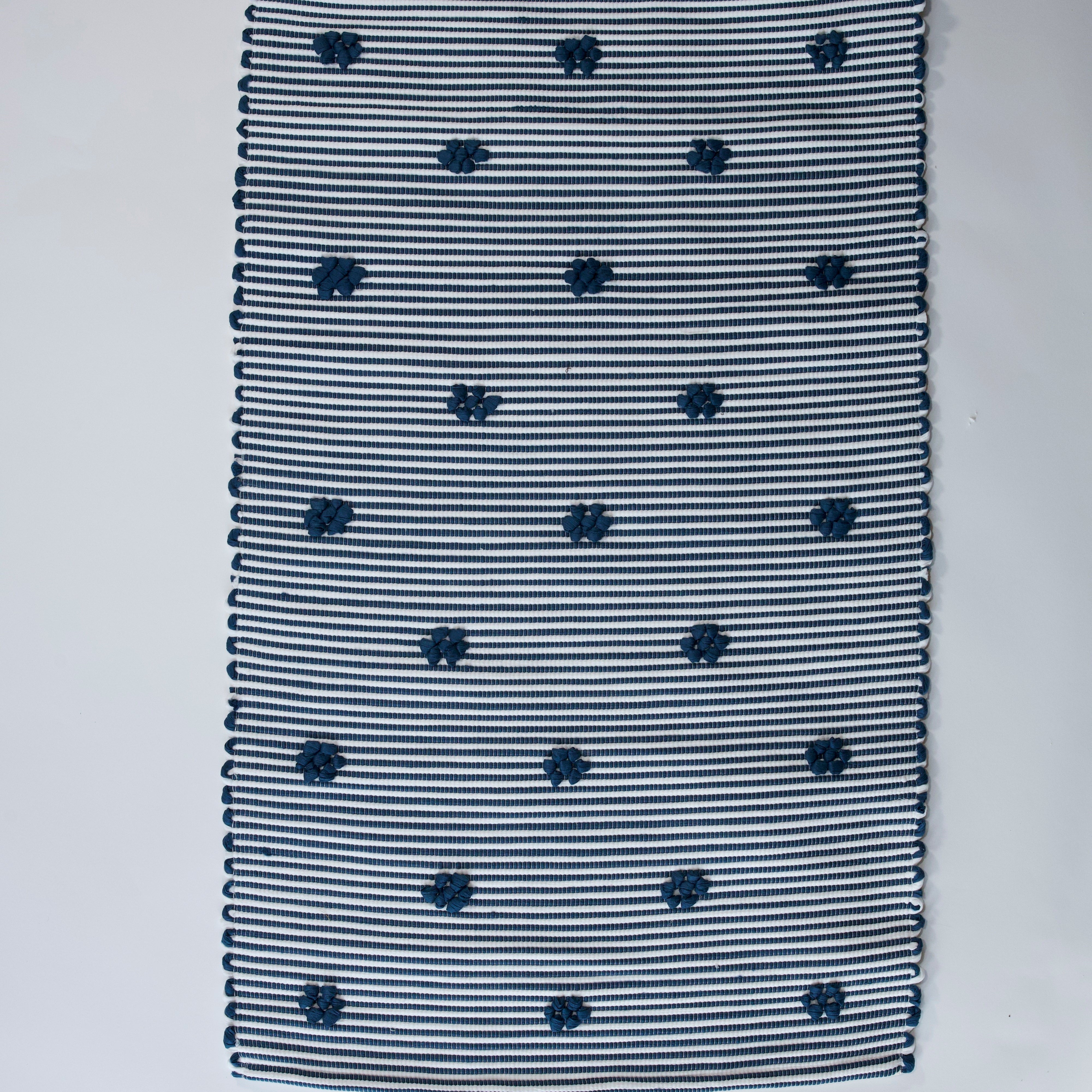 A rectangular navy blue accent rug with small daisy shaped accents scattered across it. 