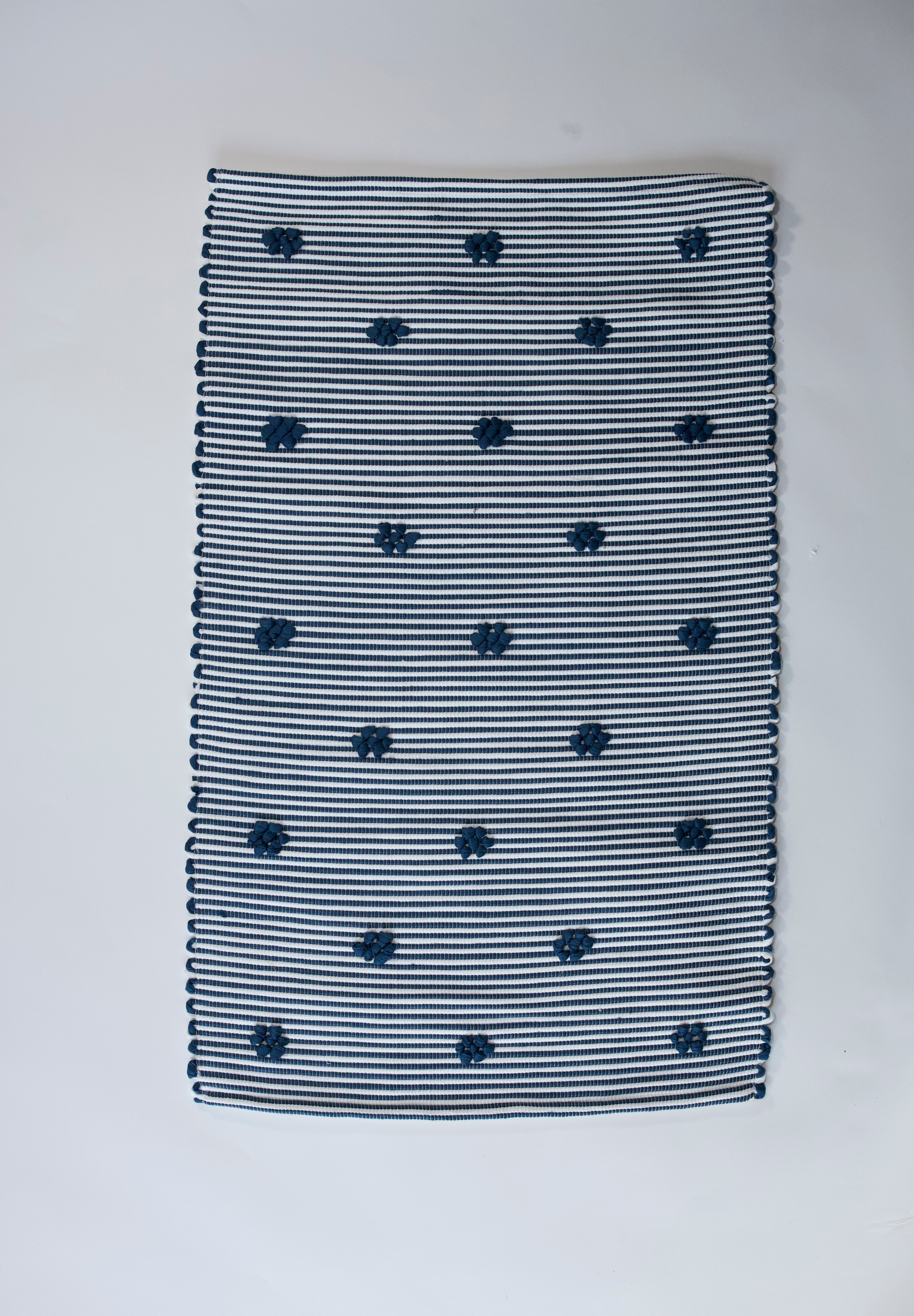 A rectangular navy blue accent rug with small daisy shaped accents scattered across it. 