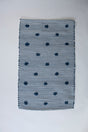 A rectangular navy blue accent rug with small daisy shaped accents scattered across it. 