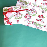 Styled flat lay of mouse-themed holiday wrapping paper with red ribbon and gift tag.