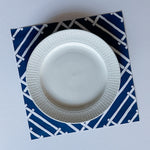 a square blue paper placemats with a white bamboo trellis design called "Island House" from Madcap Cottage.
