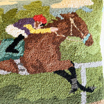 a close up of a derby day pillow featuring a horse and a jockey.