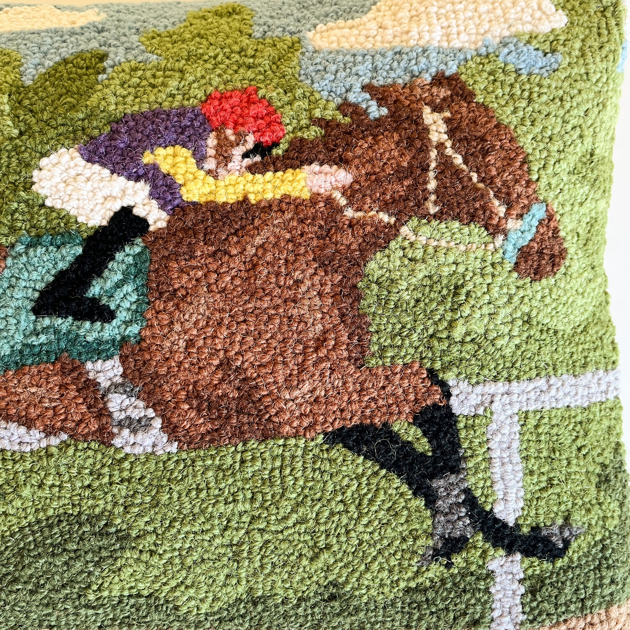 a close up of a derby day pillow featuring a horse and a jockey.