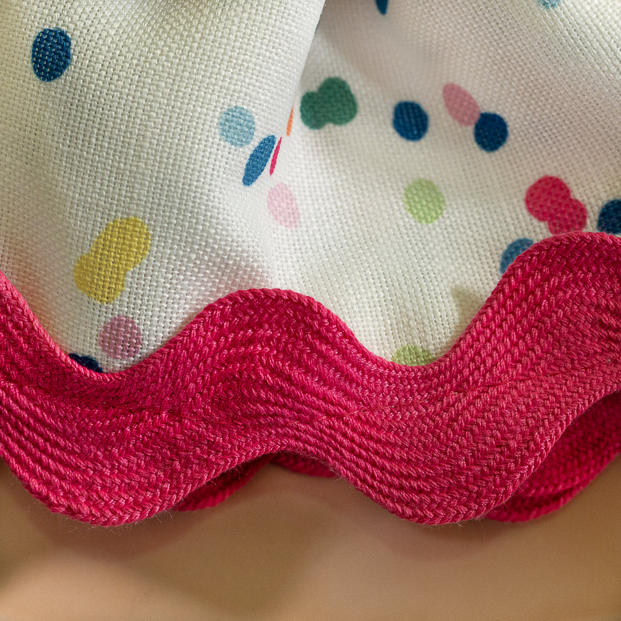 a close up of Springtime confetti multicolor cloth dinner napkin with ric rac trim from Madcap Cottage on a tan background.
