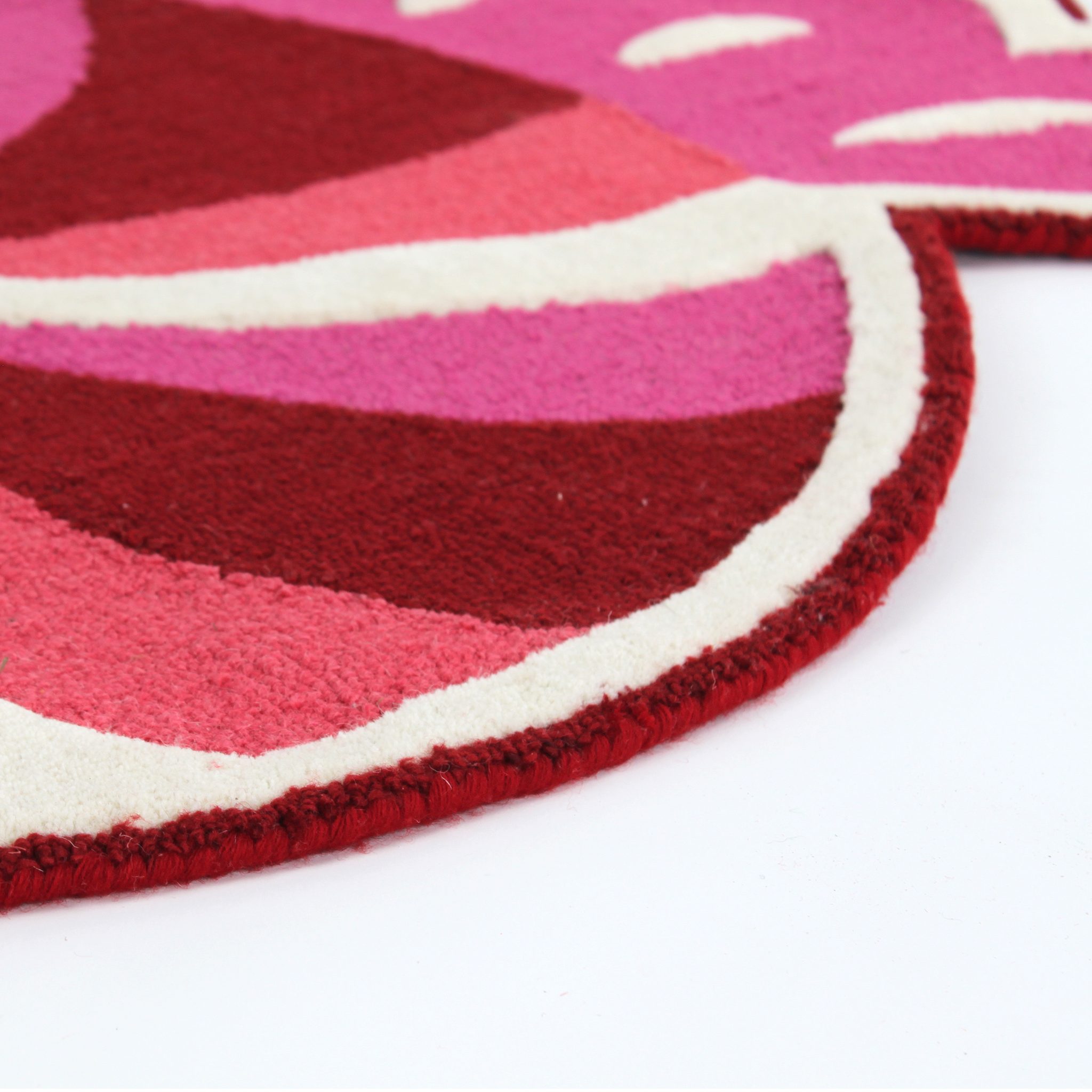 close up detail of A Christmas rug in the shape of a wrapped red, white and pink candy. 