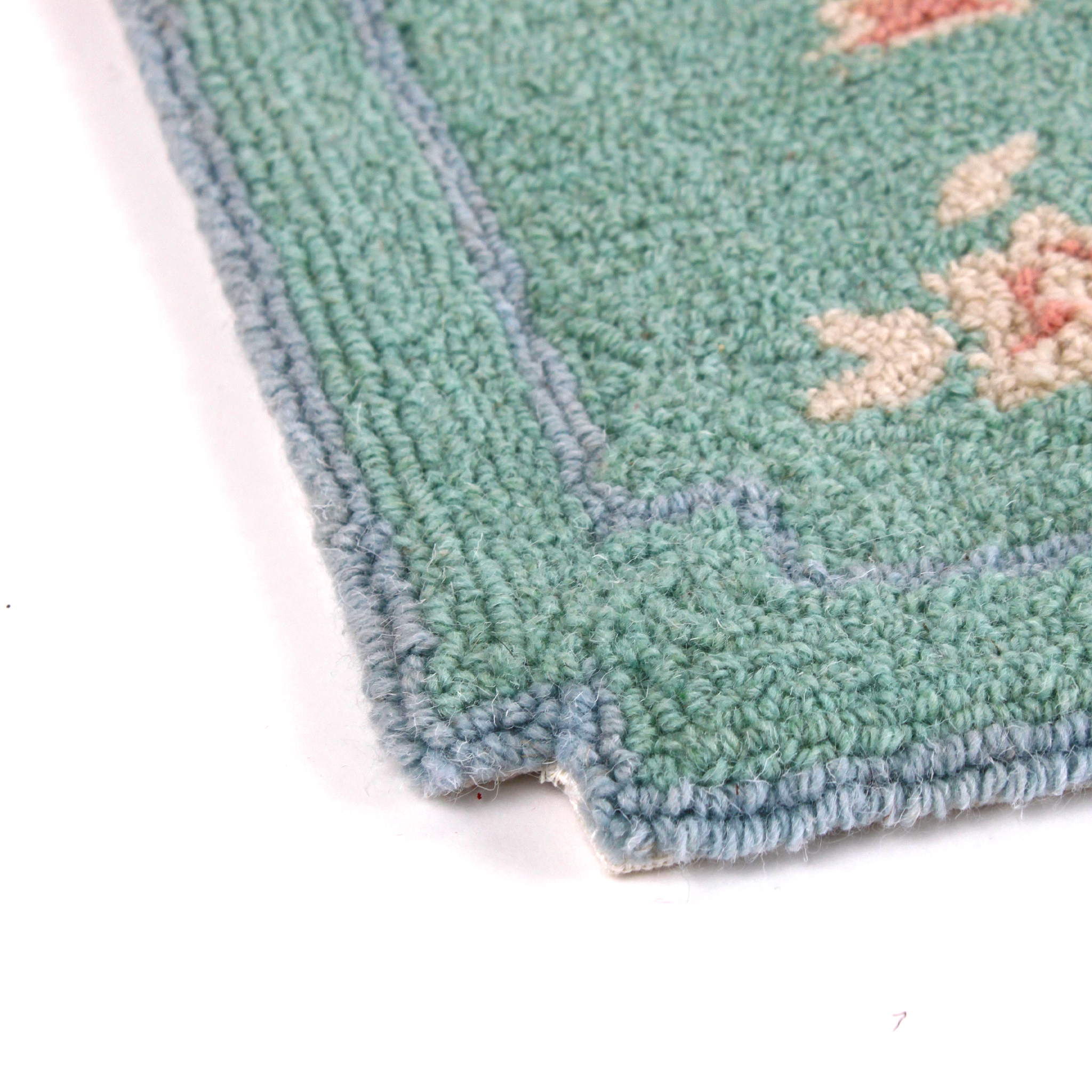 close up detail of A small pink and green rug with chinoiserie motifs.