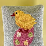 close up of A purple easter pillow with two easter eggs with a yellow chick on top