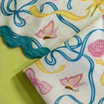 A close up of Bunnies and bow print cloth dinner napkins  with ric rac in multicolor against a light green background.