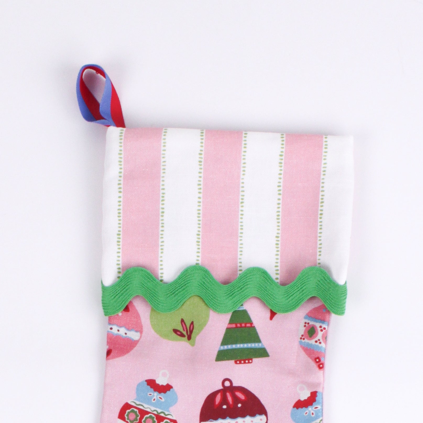 A close up of a pink Christmas stocking with colorful ornaments on a white background