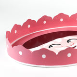 close up look of a Hand-Painted Metal Christmas Santa Tray featuring a cheerful Santa Claus face with a red hat on a pink circular background with scalloped edges.