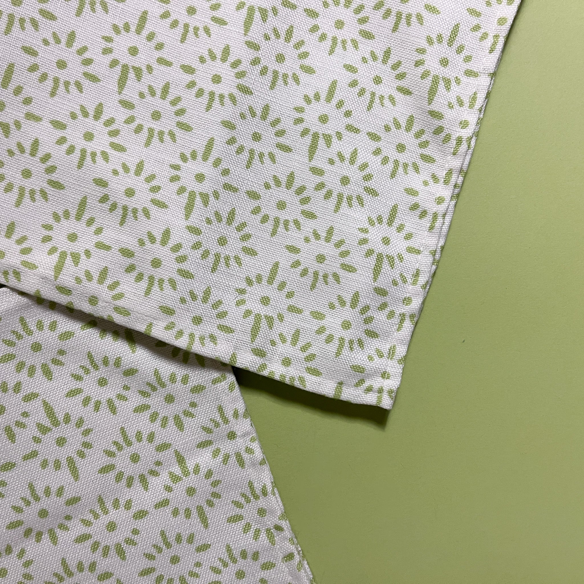close up of two white and celery green cloth dinner napkin with a painterly motif